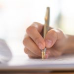 mao-com-caneta-sobre-o-formulario-de-inscricao