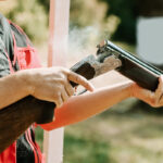 man opens the shotgun bolt after one shot with smoke