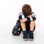 Portrait of an upset sad little kid with backpack