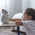 A little girl plays with her teddy bear.