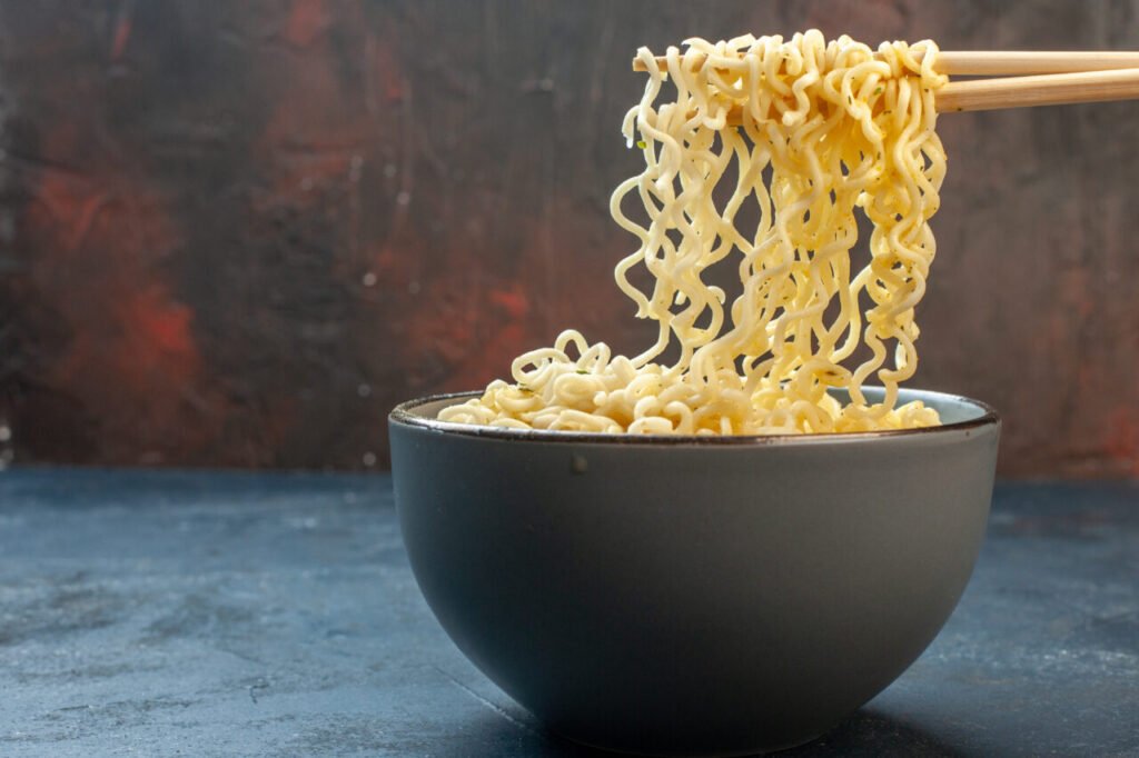 bottom-view-chopsticks-asian-ramen-noodles-bowl-dark-table-waribashi