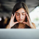 Stressed busy tired young girl in working on her report in front of laptop in the cafe