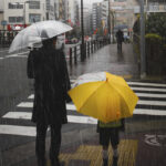 Family crossing a road on rainy day